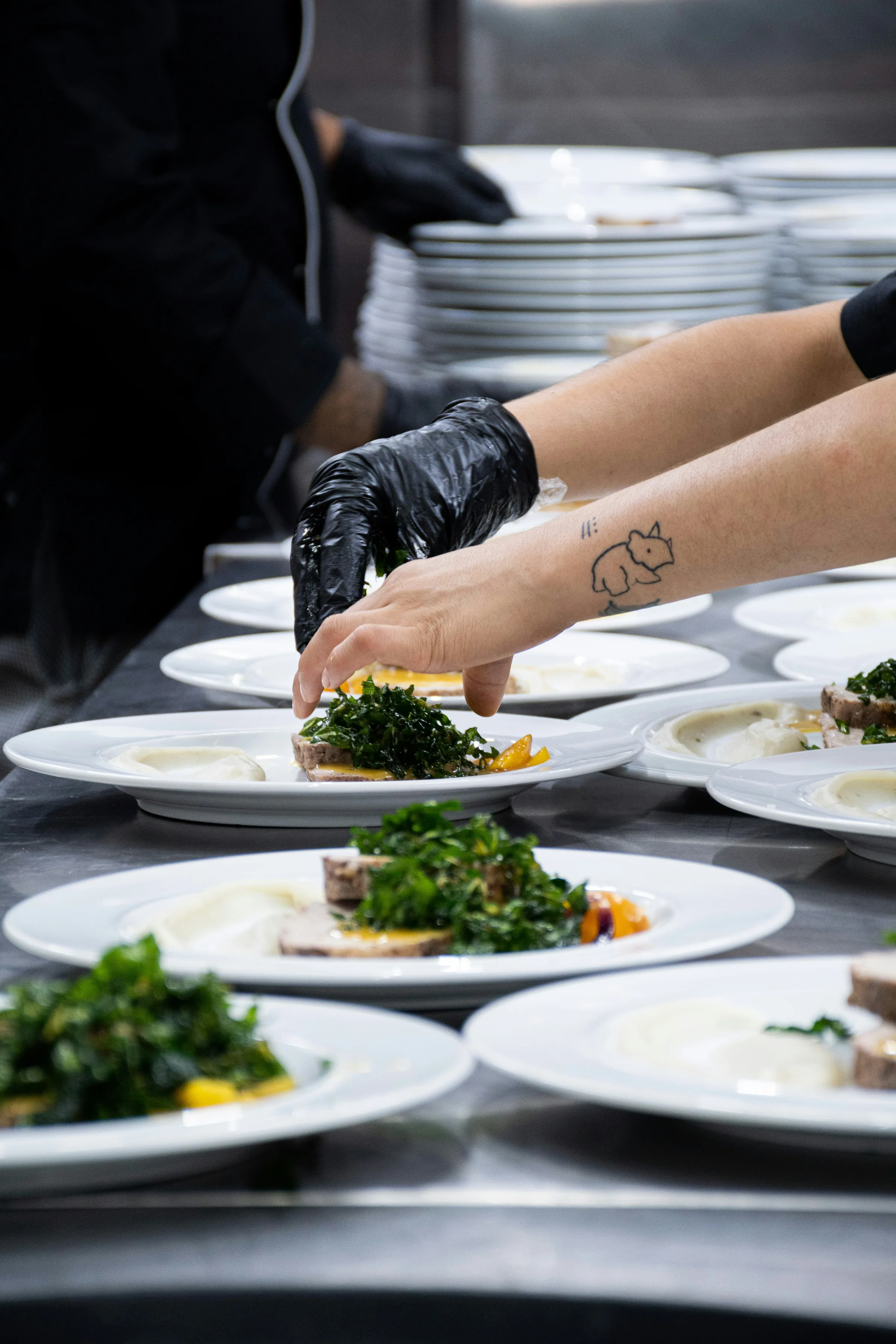 Chef aux avant-bras tatoués dressant une assiette avec précision